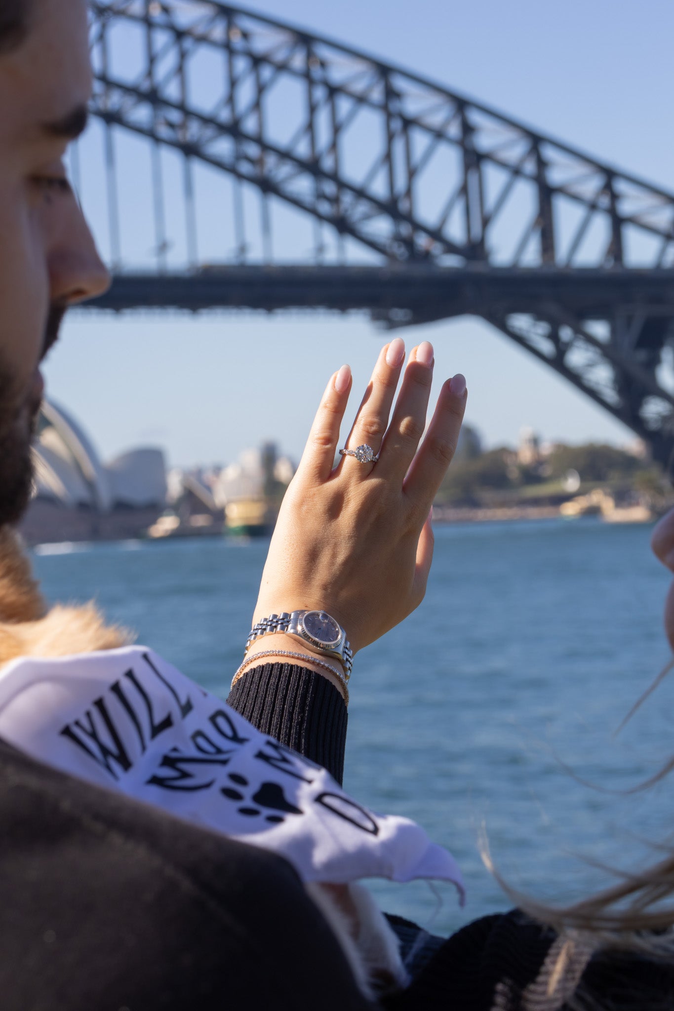 Person holding hand with ring near Sydney Harbour Bridge