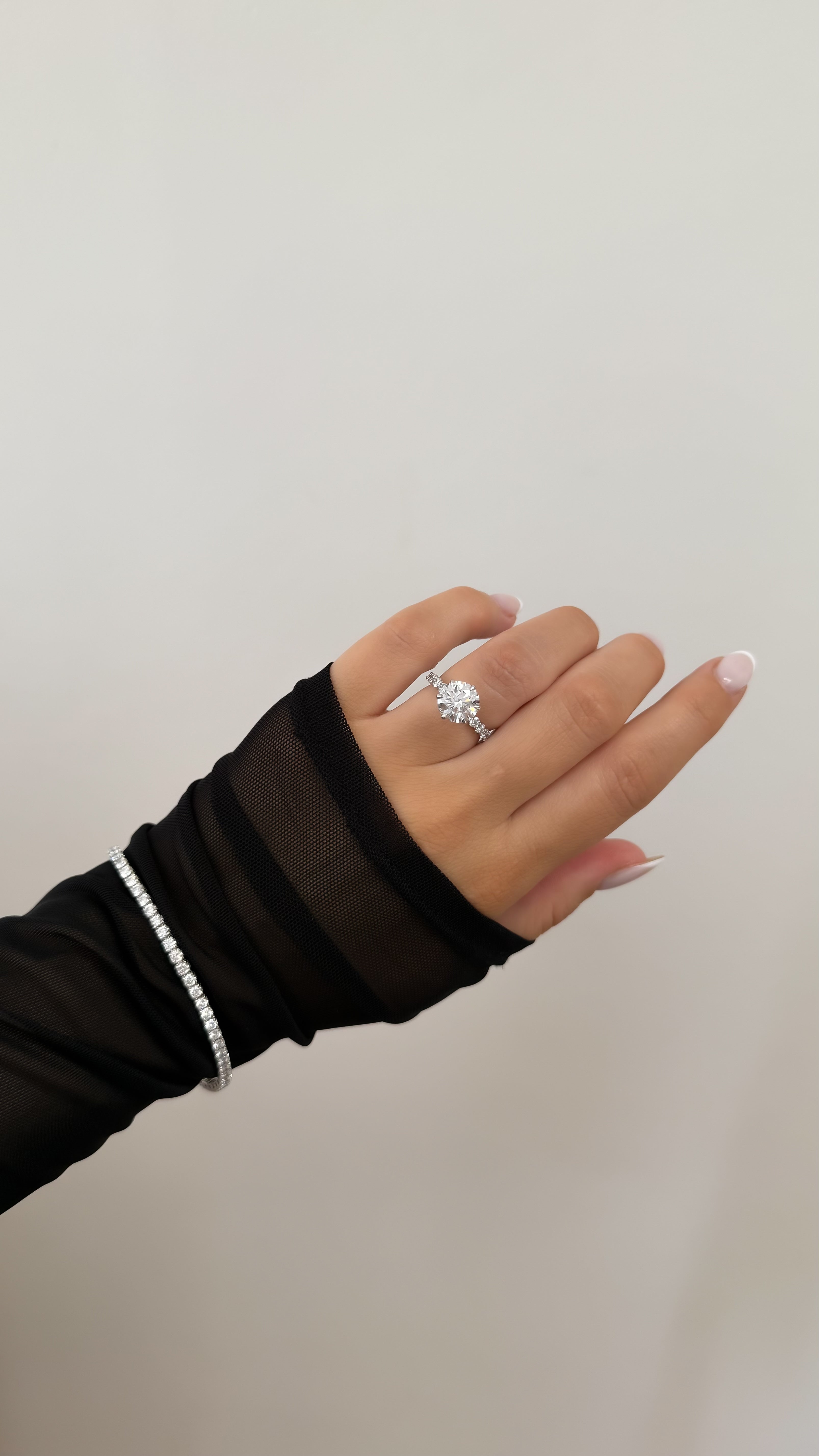 Hand wearing a Platinum ring featuring a round diamond with a plain background